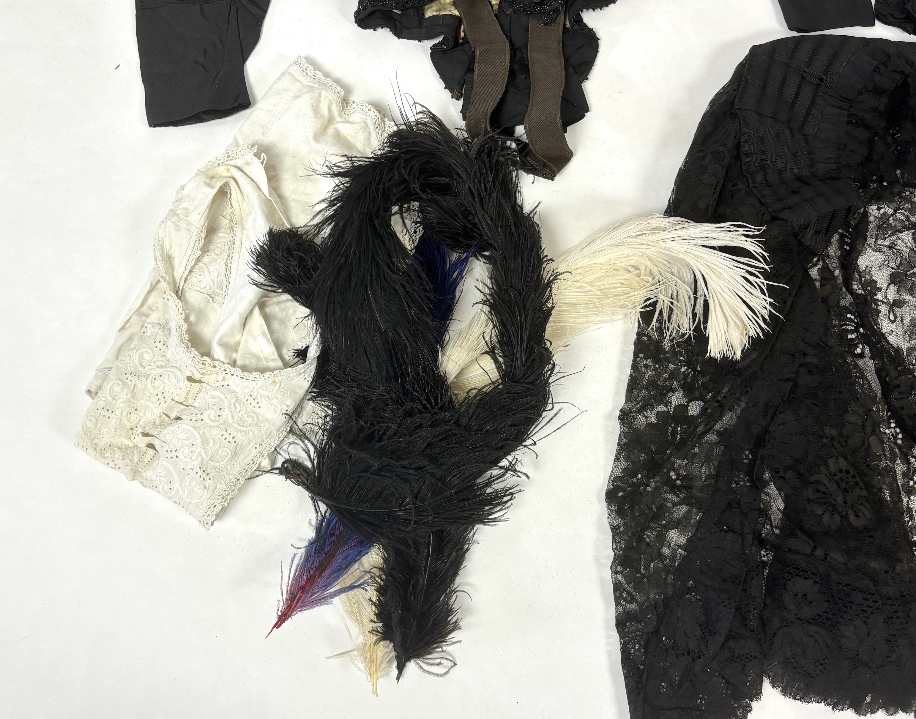 Two lady's Victorian black satin and lace, bead trimmed bodices, together with a black lace cape, a black satin cape, a small collection of coloured feathers and a child’s white worked pinafore
